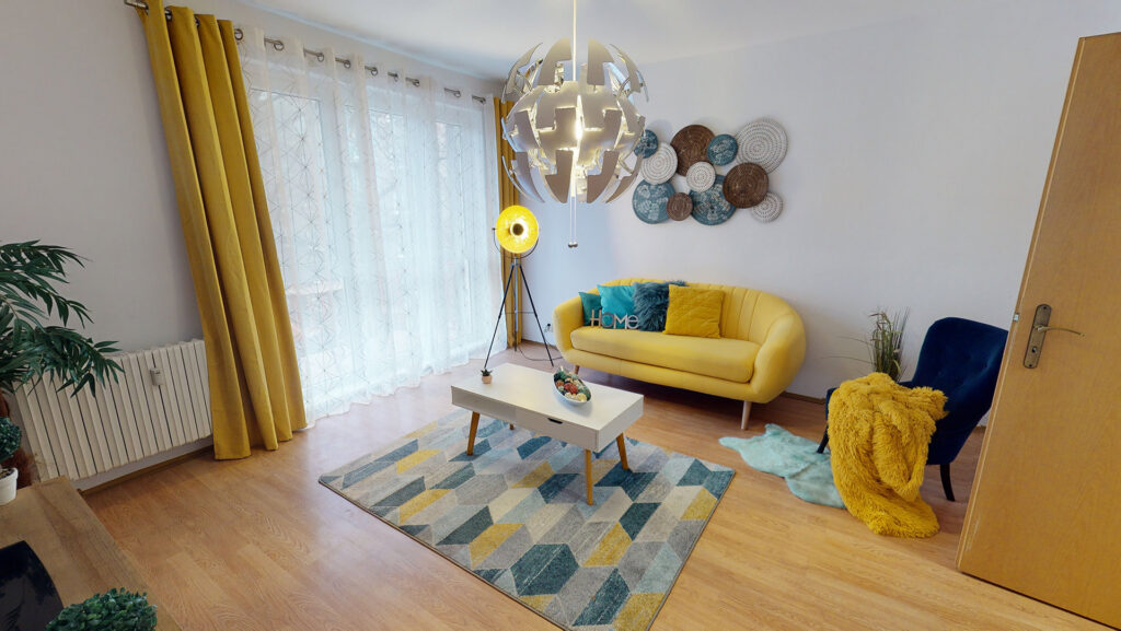 Obývačka so žltou pohovkou a farebným kobercom — ukážka home stagingu