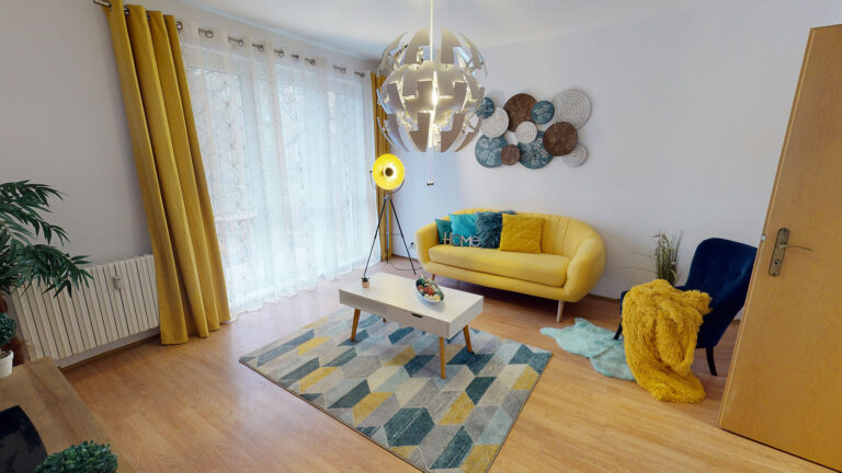 Obývačka so žltou pohovkou a farebným kobercom — ukážka home stagingu