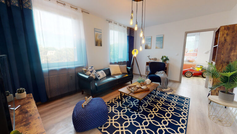 Obývačka s tmavomodrou sedačkou a vzorovaným kobercom — ukážka home stagingu